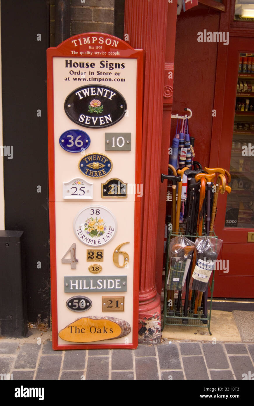 Vari segni della casa e il numero delle placche più una selezione di bastoni da passeggio per la vendita al di fuori di un negozio nel Regno Unito Foto Stock