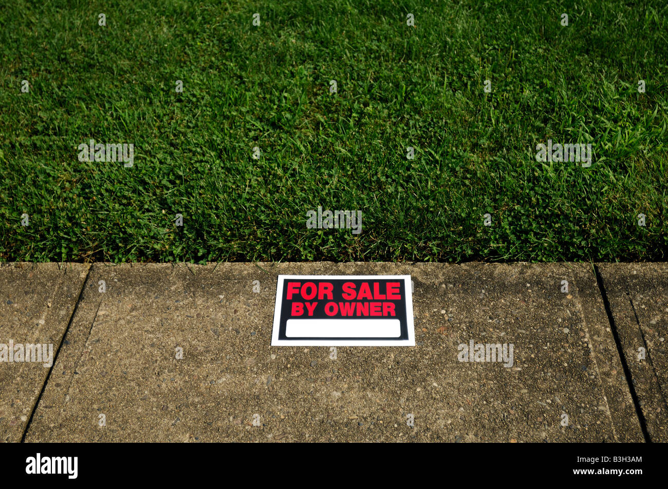 Una proprietà per la vendita dal proprietario sign su erba verde e il marciapiede Foto Stock