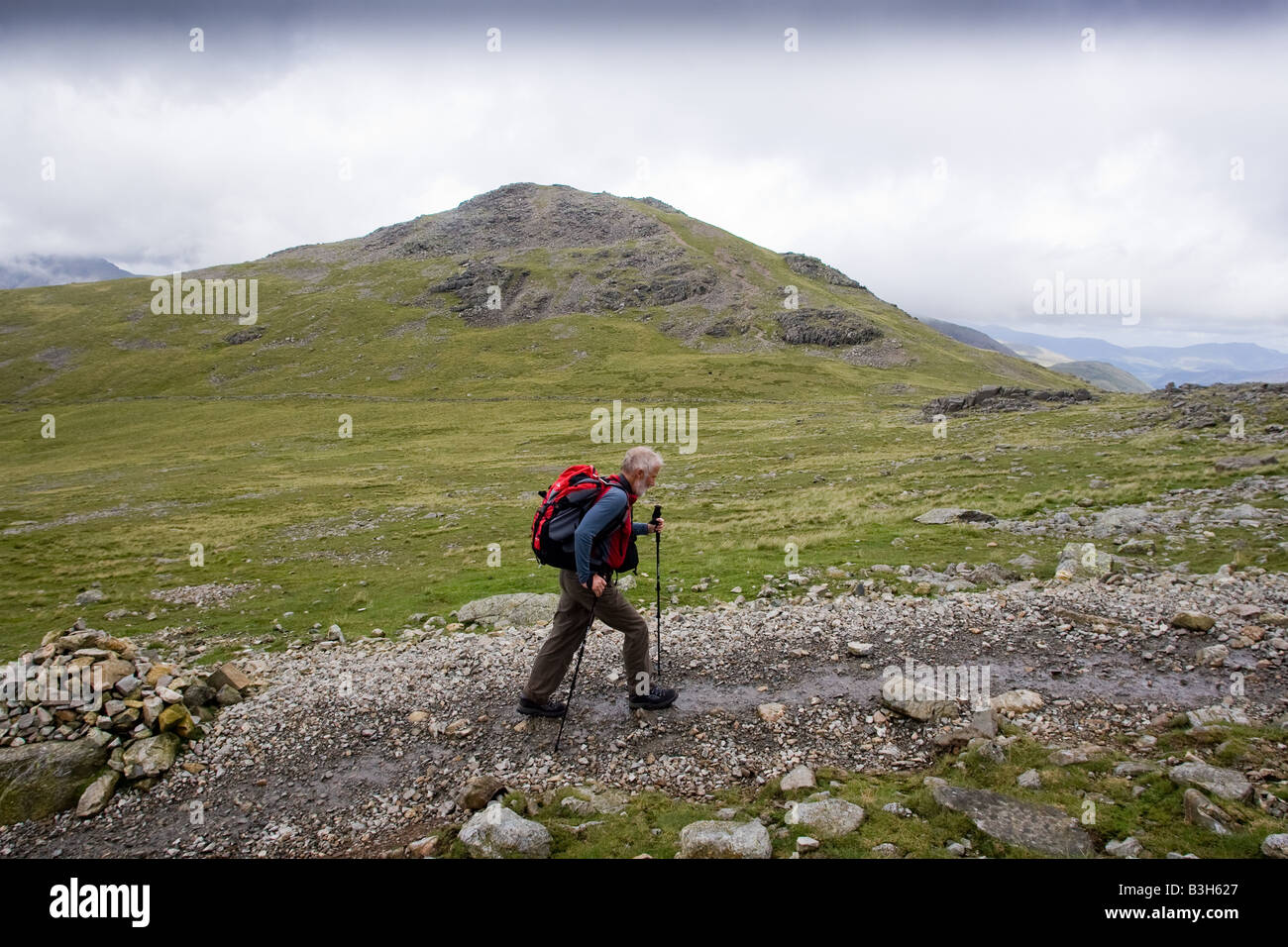 Sir Chris Bonington cammina verso il vertice di Scafell Pike, la montagna più alta d'Inghilterra. In fondo è Lingmell Foto Stock