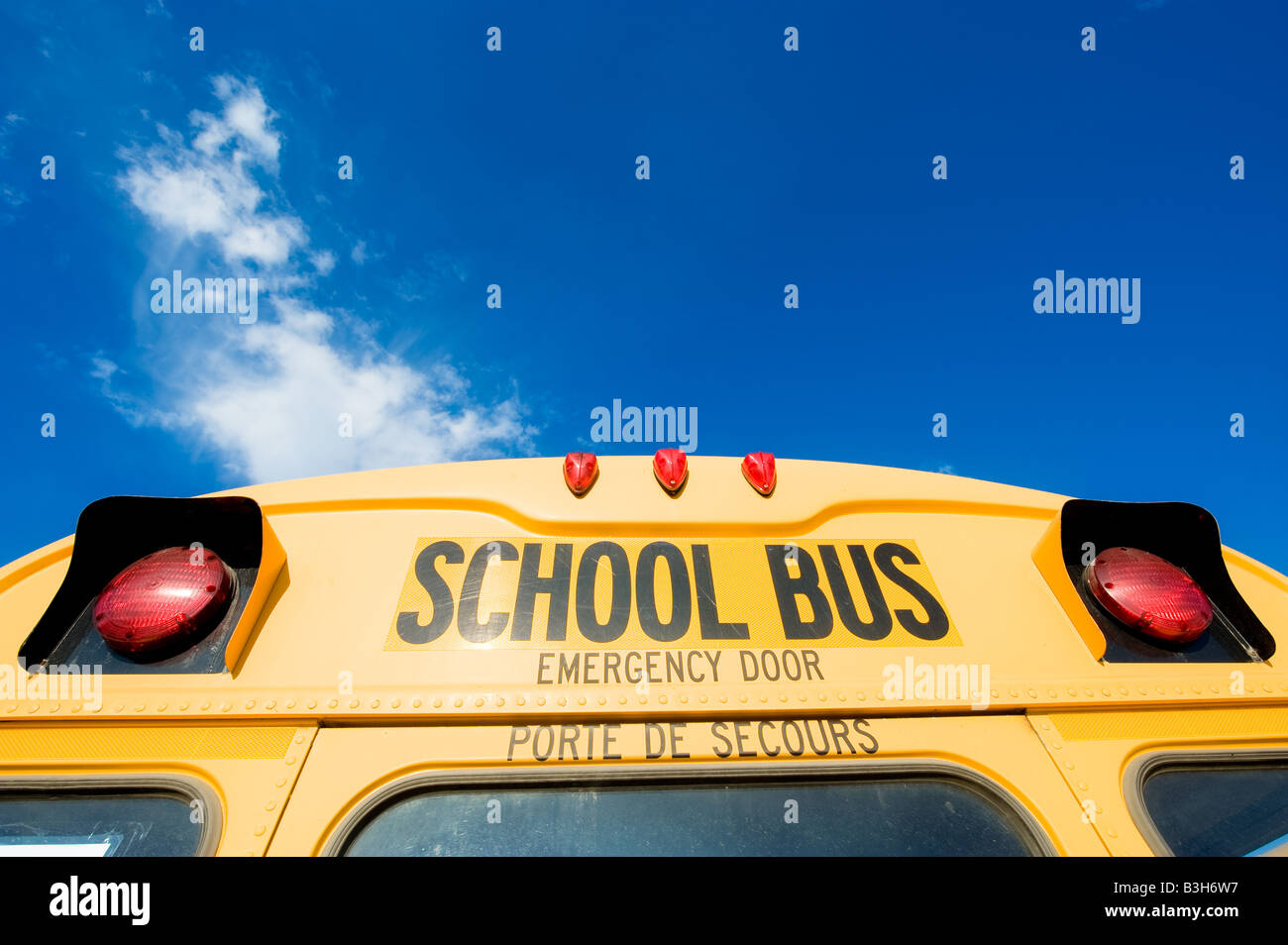 La parte superiore della porzione posteriore di un giallo moderno scuola bus contro il blu intenso del cielo. Foto Stock