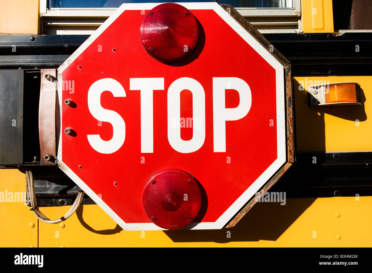 Il grande segno di stop rosso segnale braccio sul lato di un giallo scuola bus per avvisare gli automobilisti di studenti. Foto Stock