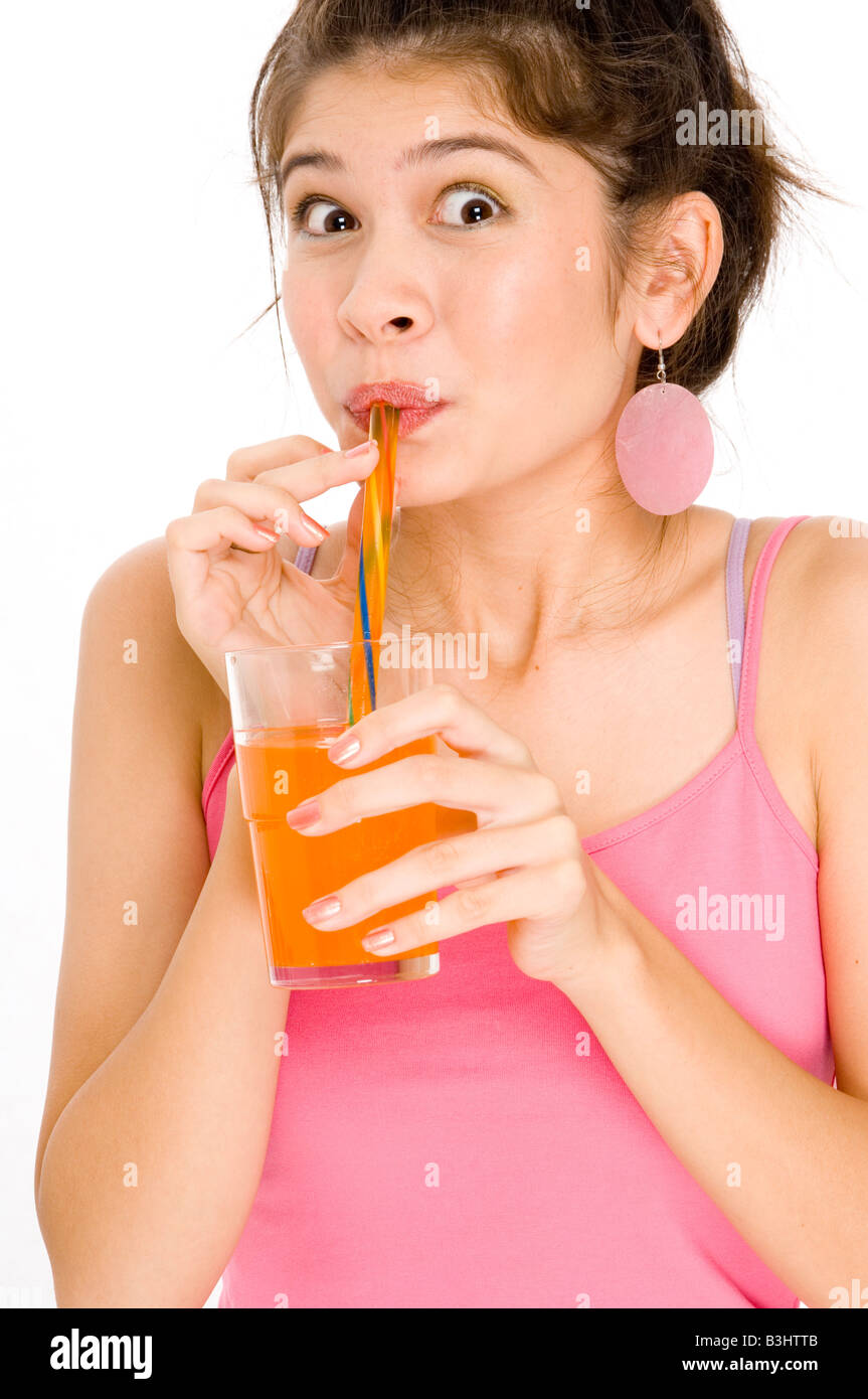Una giovane ragazza sembra sorpreso come ella beve la sua bevanda a base di arancia Foto Stock