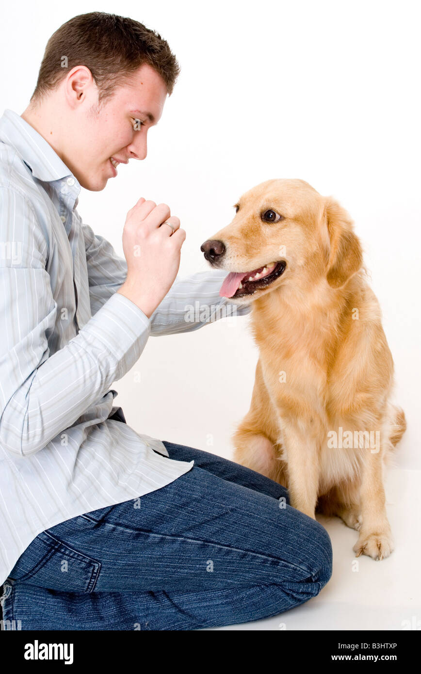 Un giovane uomo di addestramento il suo cane dando a trattare come una ricompensa Foto Stock