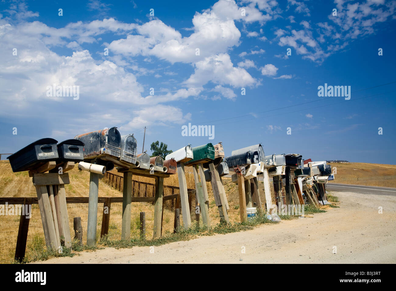 Colpo lungo una fila di cassette postali nelle zone rurali la valle centrale della California USA contro un profondo cielo blu Foto Stock