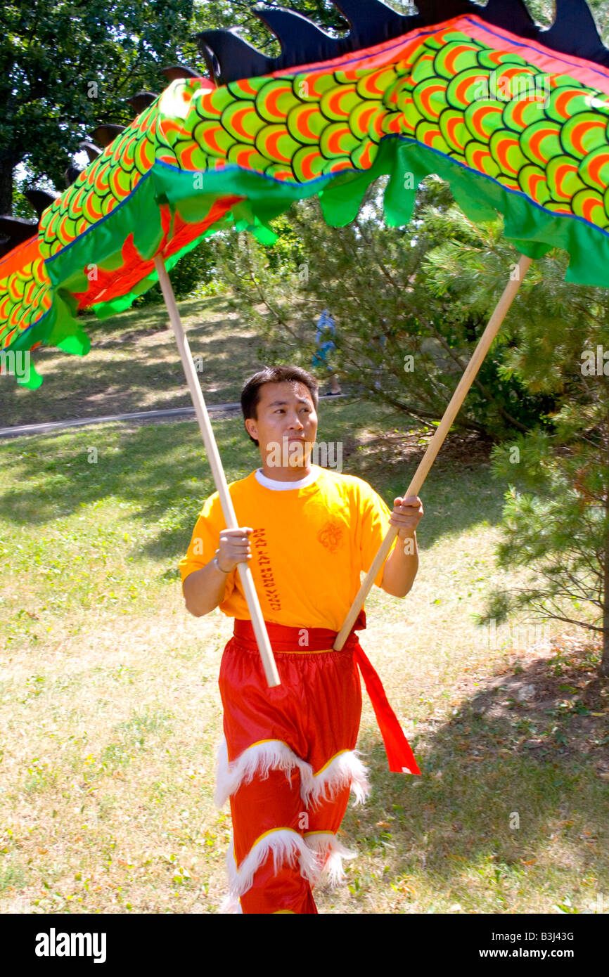 La danza membro del team aiuta a trattenere il cerimoniale drago con due poli. Dragon Festival Lago Phalen Park St Paul Minnesota USA Foto Stock