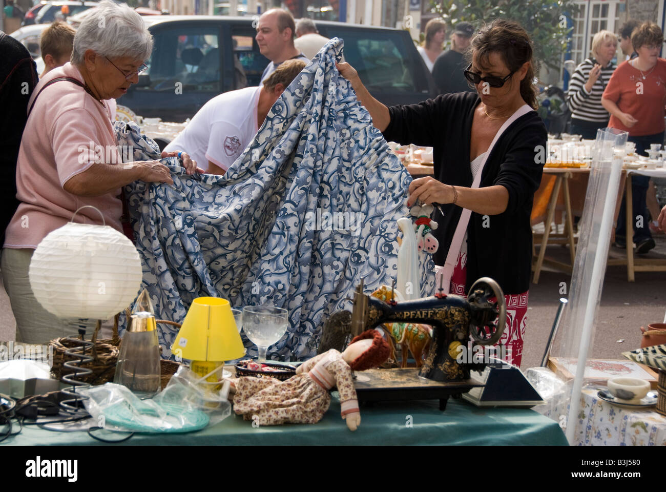 Il mercato settimanale a Barneville, Normandia, Francia. Due clienti ispezionano le tende da uno stallo brac Foto Stock