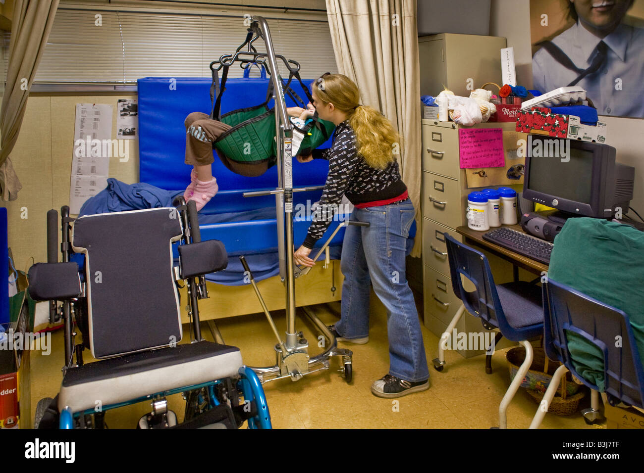 Utilizzando un servizio specializzato di Hoyer sollevare una speciale istruzione insegnante posti uno studente su un lettino per alleviare lo sfregamento provocato dal bambino s Foto Stock