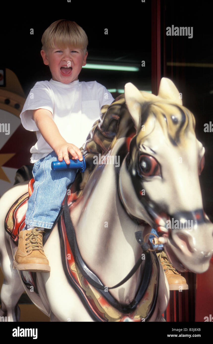 Ragazzino sulla corsa sul cavallo in sala giochi Foto Stock