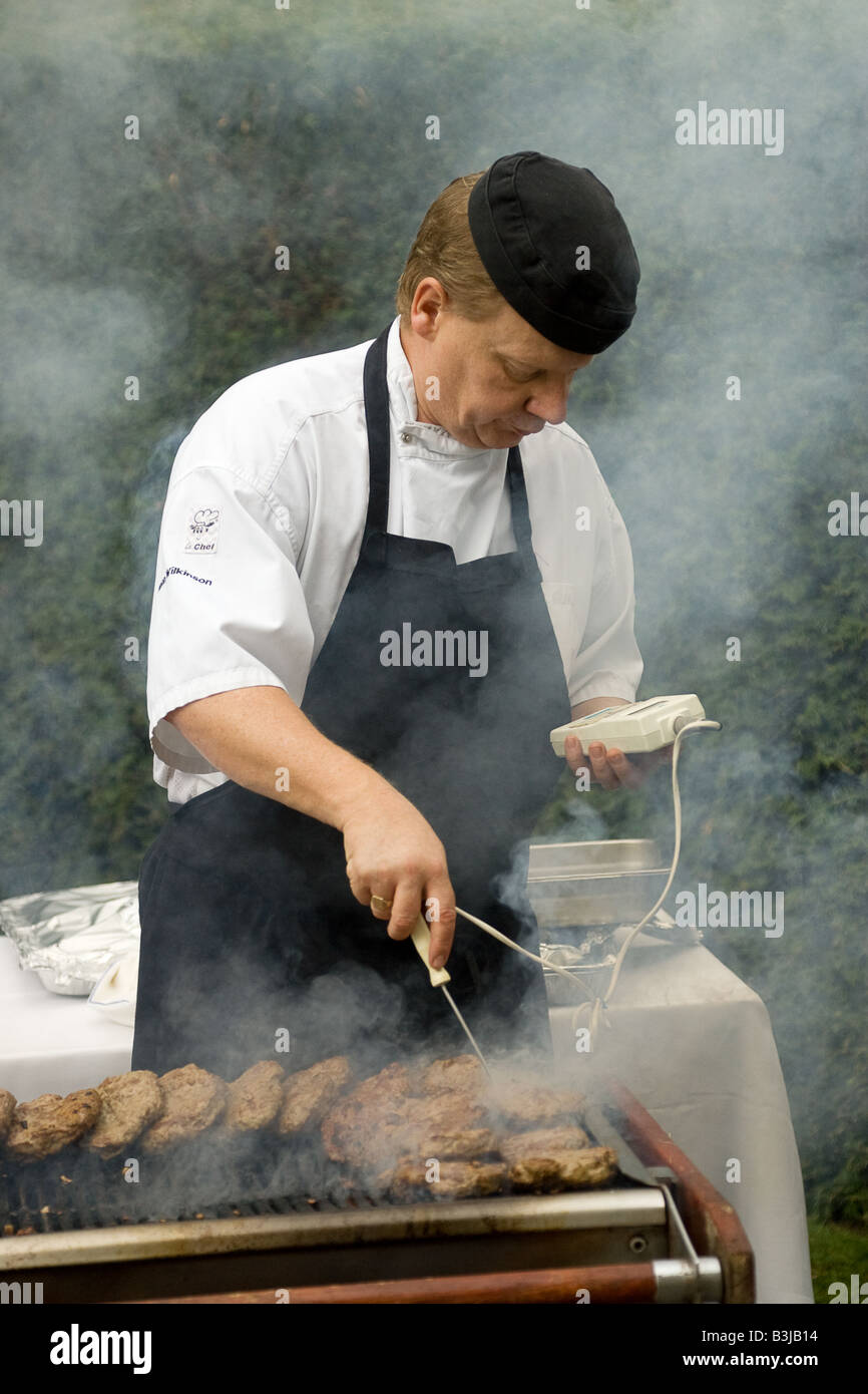 Lo chef Barbecue controllando la temperatura del cibo per assicurarvi che sia ben cotto. Foto Stock