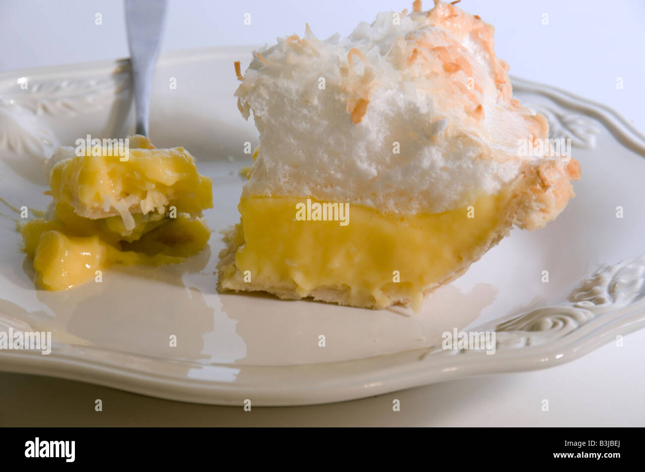 Una fetta di noce di cocco Torta di crema su una piastra bianca, con un morso su una forcella. Primo piano. Foto Stock