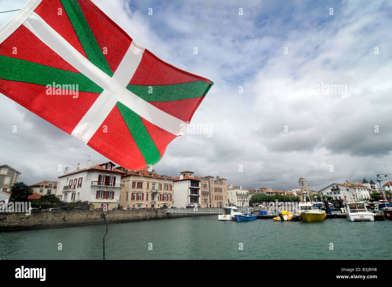 Una bandiera basca vola da una barca è il montante nel porto di St Jean de Luz, una piccola città nel Pays Basque, il sud-ovest della Francia Foto Stock