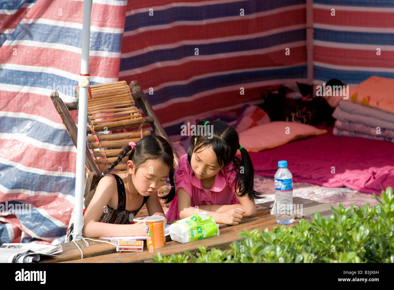 I bambini a fare i compiti di scuola in una tenda di fortuna dopo il terremoto del Sichuan il 12 maggio 2008, Cina Foto Stock