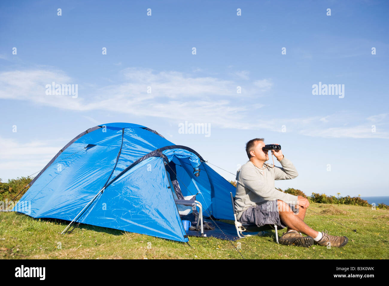 L'uomo camping all'esterno e guardare attraverso i binocoli Foto Stock