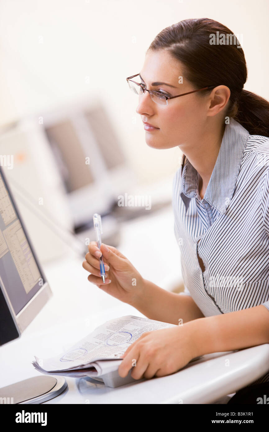 La donna nella sala computer volteggiare gli elementi in un giornale Foto Stock