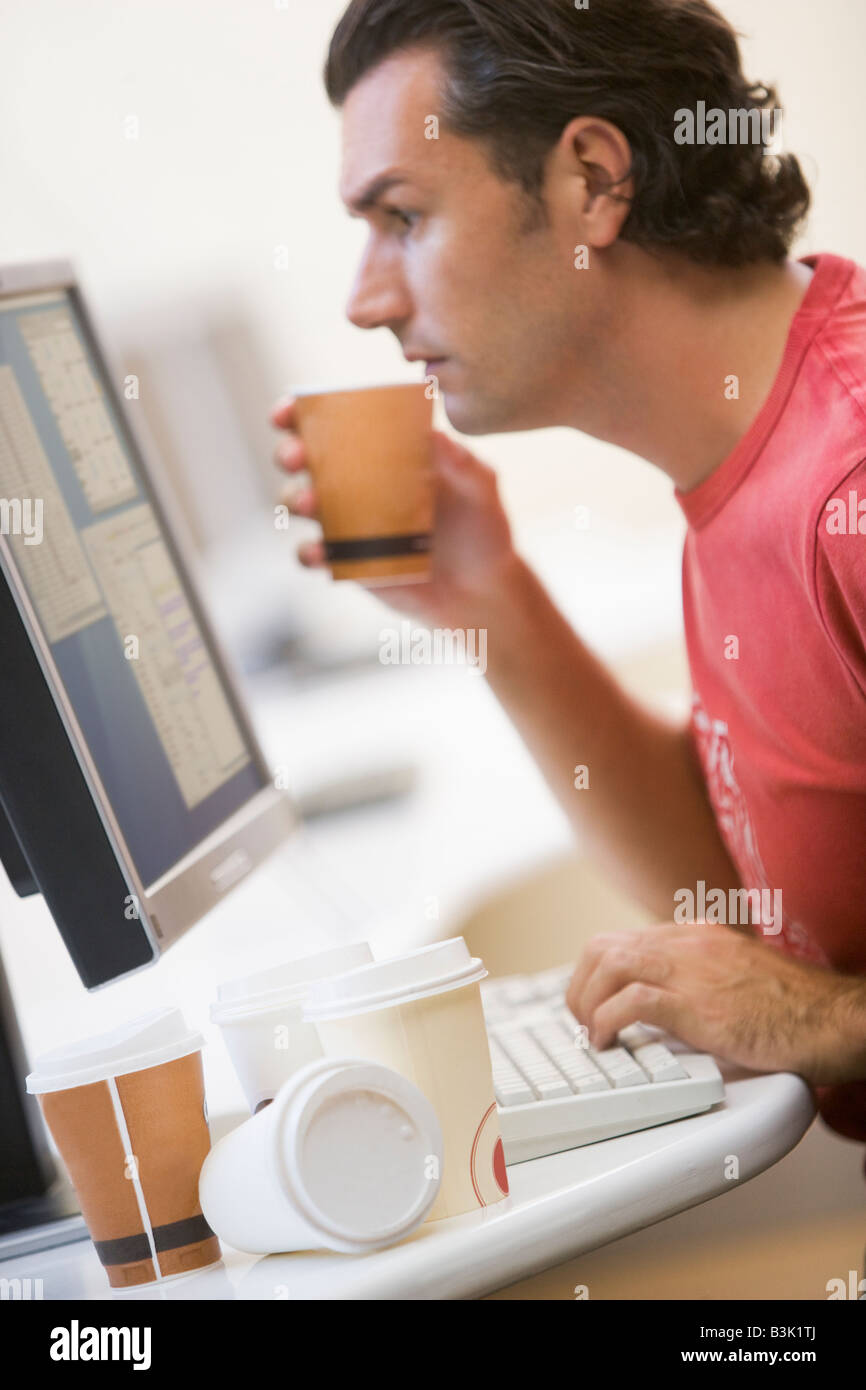 Uomo in sala computer con tante vuote le tazze di caffè Foto Stock
