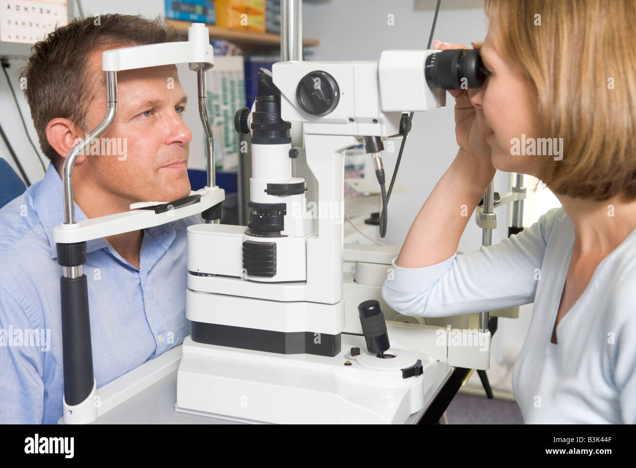 All'ottico optometrista in sala esame con uomo in cattedra Foto Stock