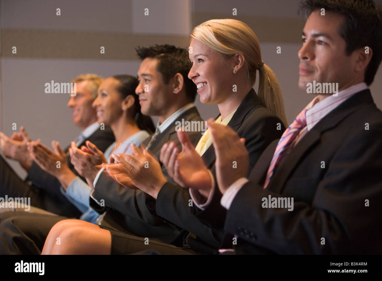 Cinque imprenditori applaudendo e sorridente in sala di presentazione Foto Stock