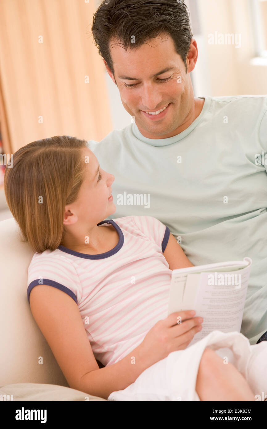 L uomo e la bambina nella sala lettura prenota e sorridente Foto Stock