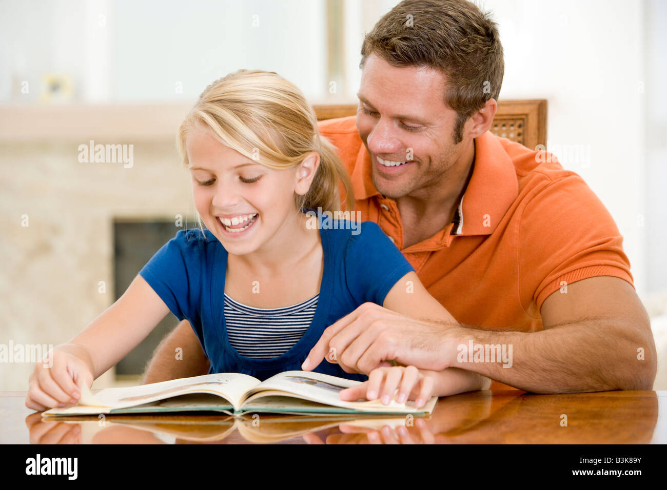 L uomo e la giovane ragazza libro di lettura nella sala da pranzo sorridente Foto Stock