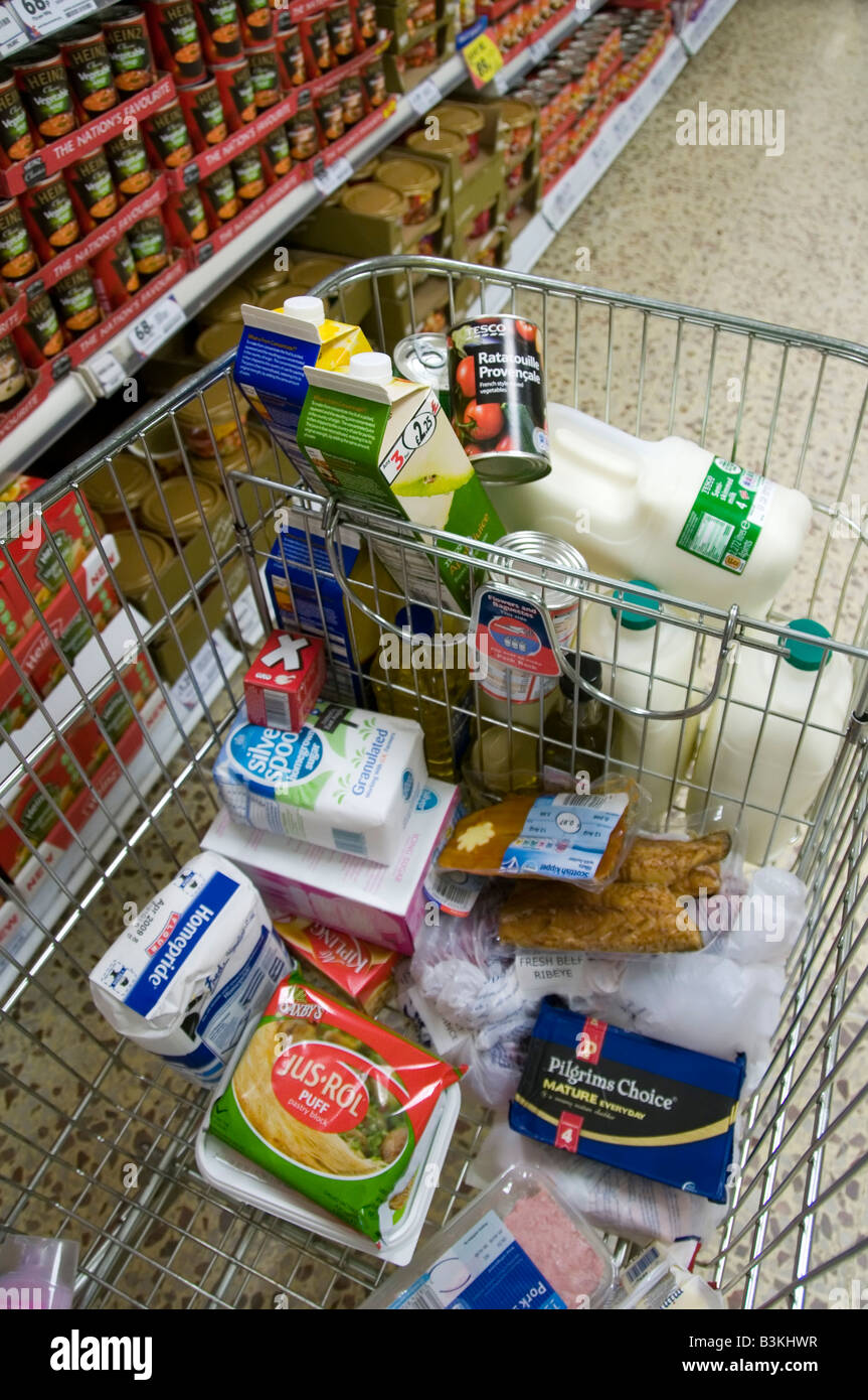 Tesco Supermarket carrello carrello per lo shopping di cibo in Aisle accanto scaffali della drogheria Inghilterra UK Foto Stock
