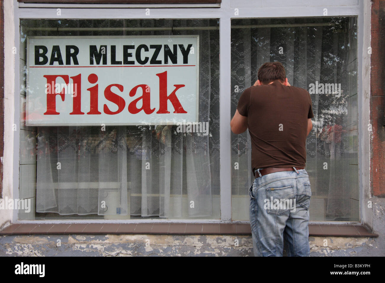 L'uomo guarda attraverso la finestra di 'Flisak' latte bar o Bar Mlecczny a Cracovia, Polonia Foto Stock