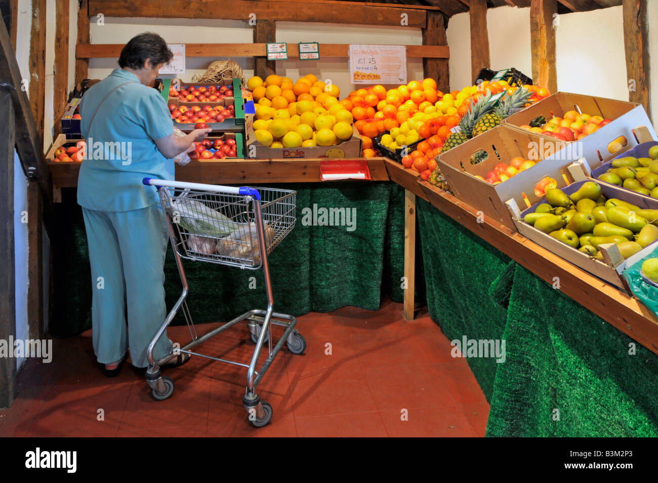 Interno del retail farm shop producono frutta sul display donna shopper e carrello Foto Stock