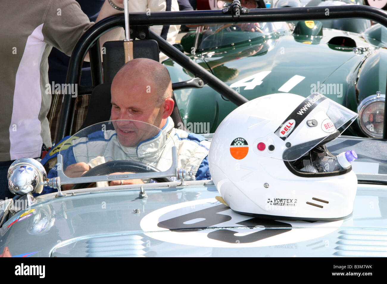 Racing driver in un classico racing car hemet sul cofano in pit lane a Silverstone Foto Stock