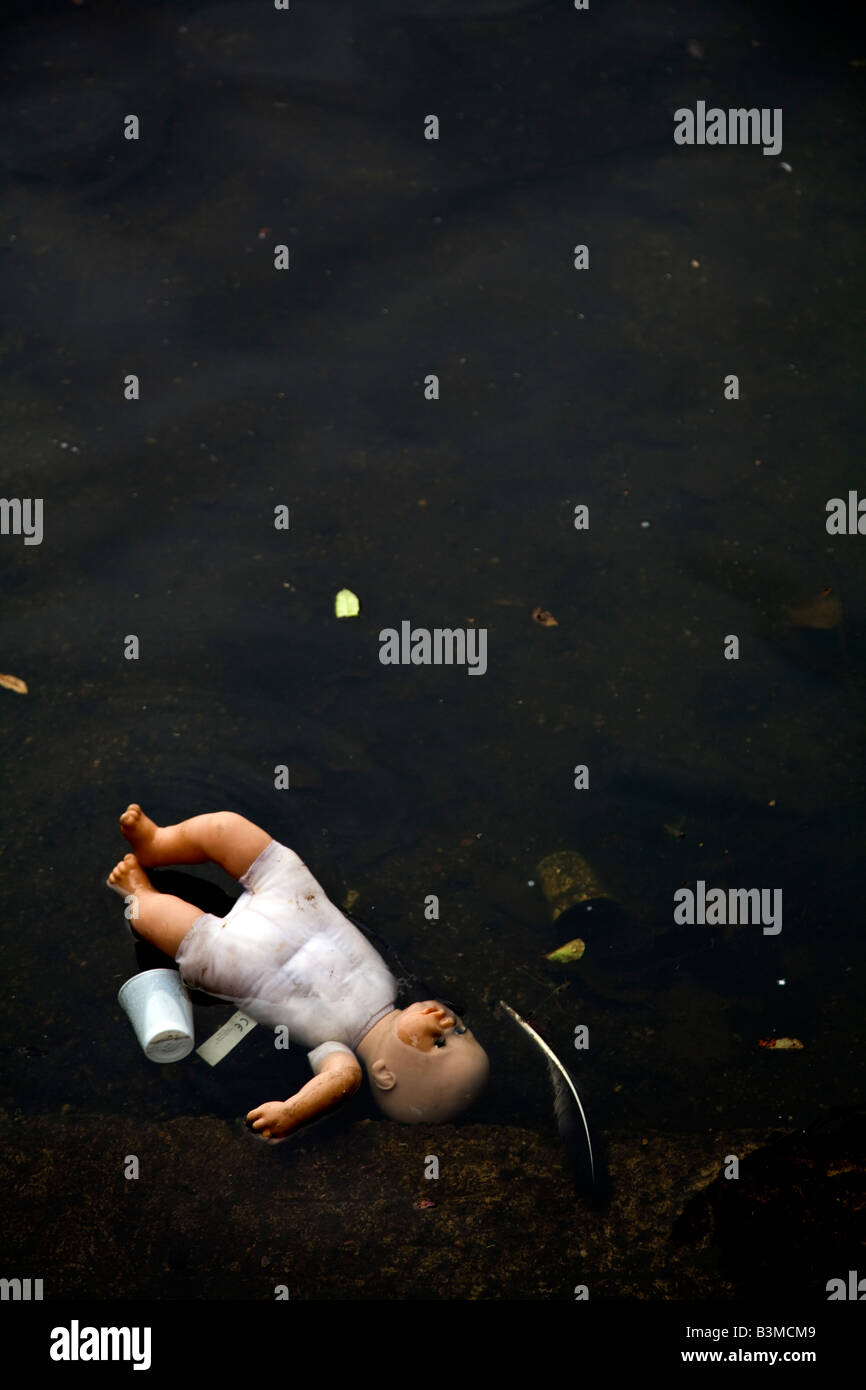 Scartato bambola per bambini in acqua con la spazzatura Foto Stock