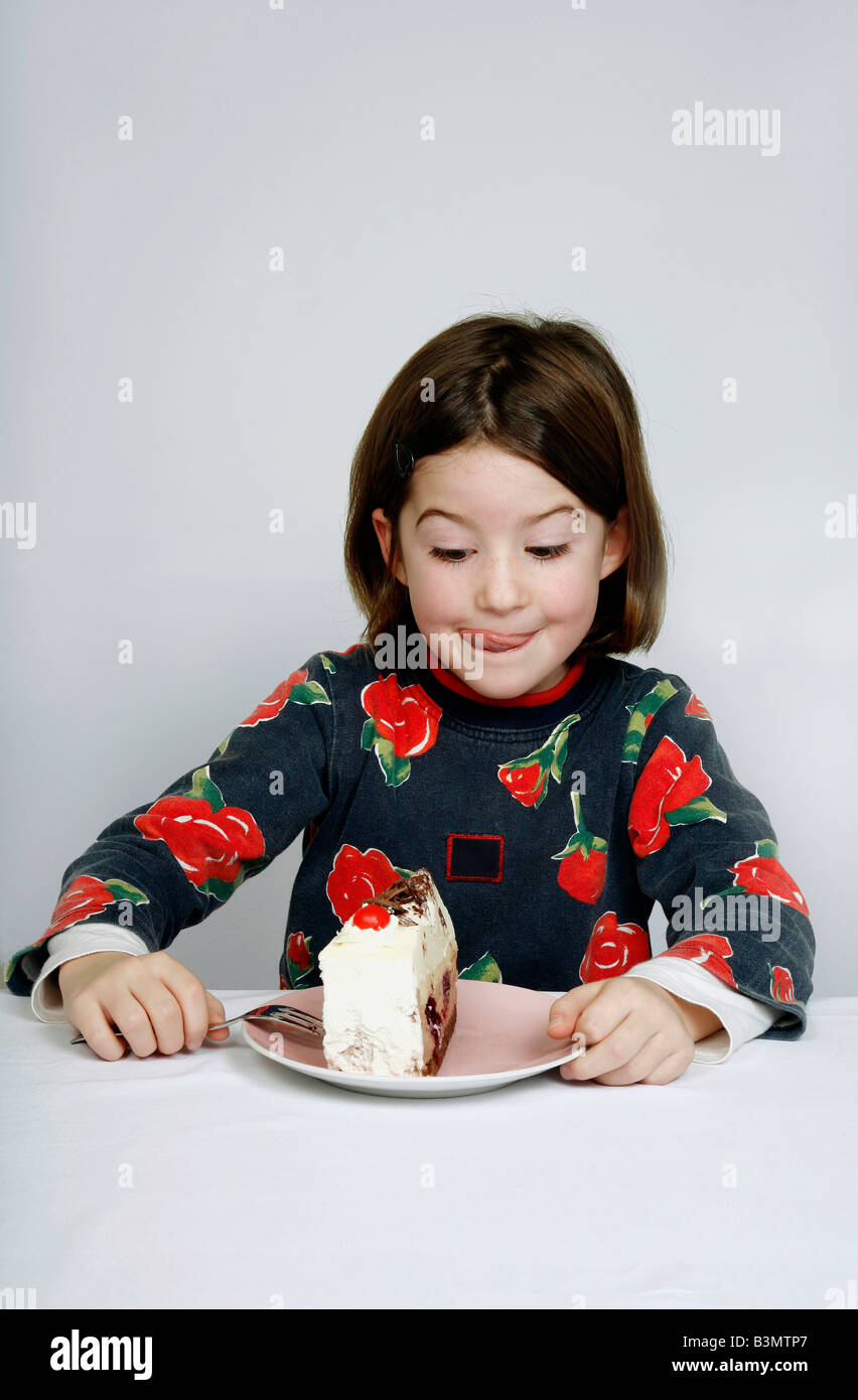 Ritratto di una ragazza (8-9) di mangiare una fetta di torta Foto Stock