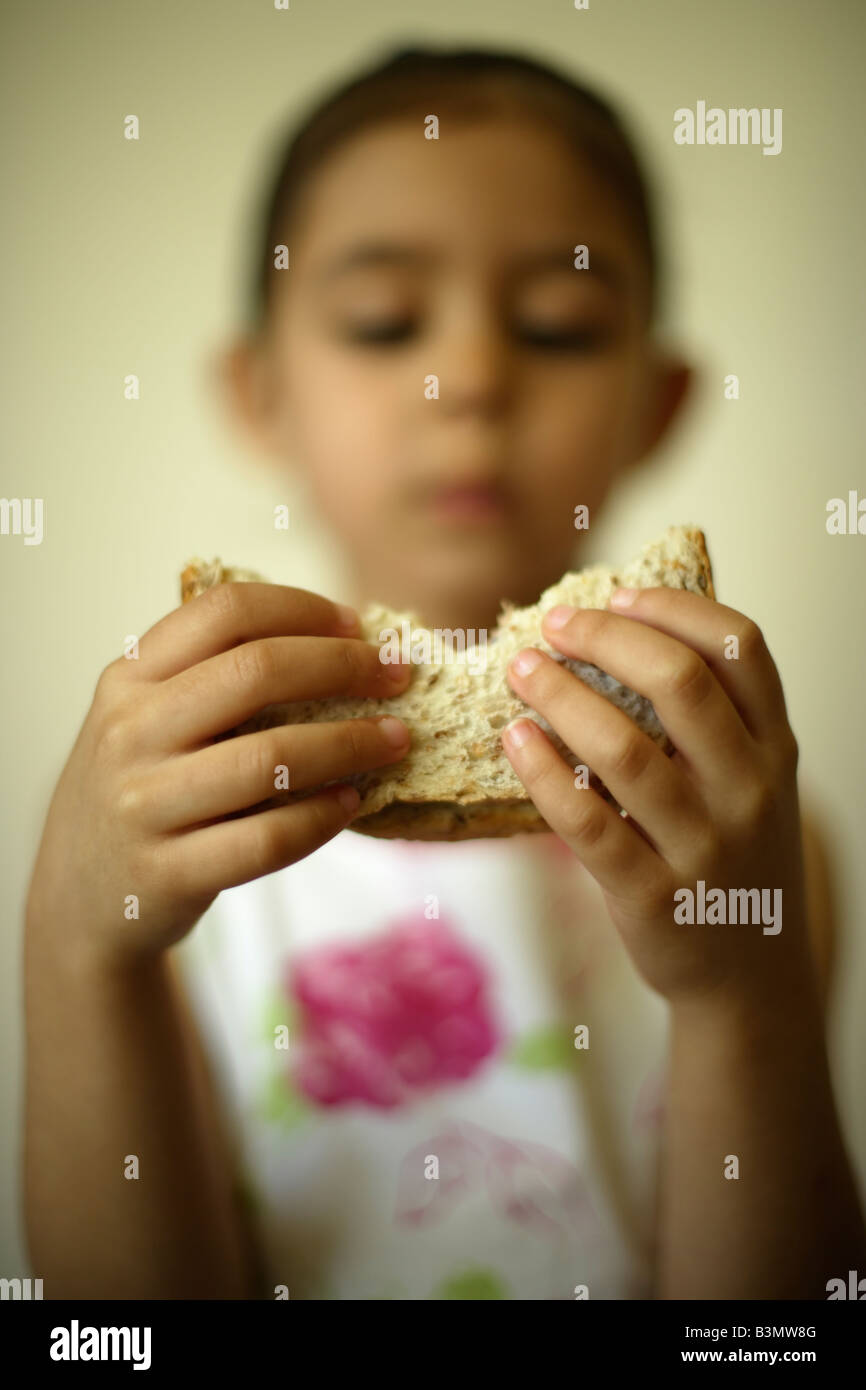 Bambina di cinque anni morde sandwich Foto Stock