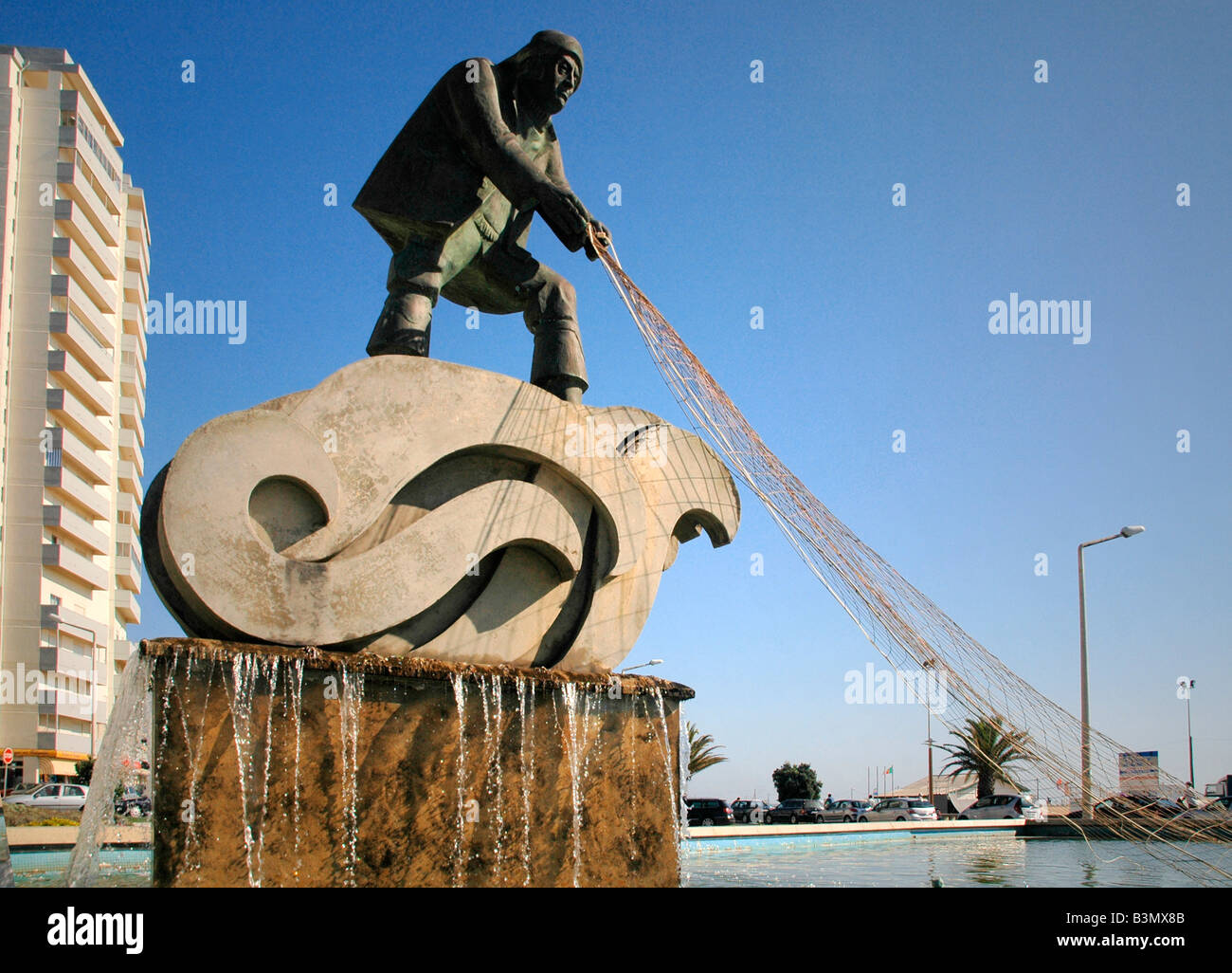 Una fontana e la statua di un pescatore e reti nel centro della città di Figueira da Foz - La costa d'argento - Portogallo. Foto Stock