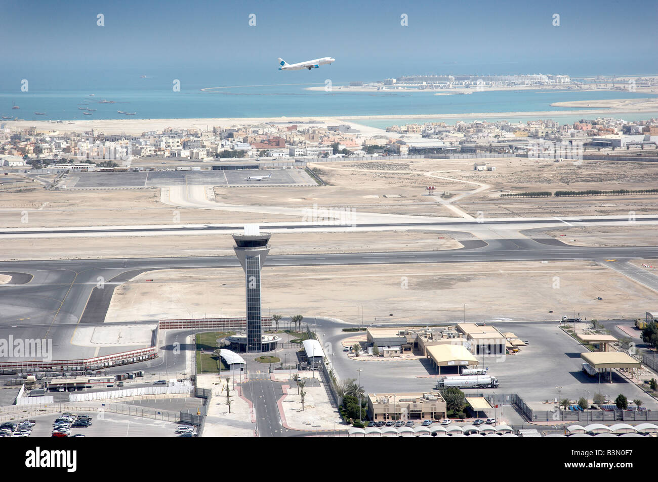 In Bahrain la torre di controllo e delle piste di atterraggio e di decollo fotografato dall'aria con un aereo in fase di decollo. Foto Stock