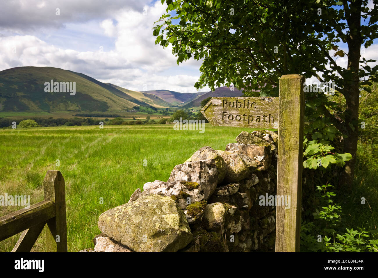 Tipico Lake District inglese scena con un cartello in legno post, secco muro di pietra e gate Cumbria, England, Regno Unito Foto Stock