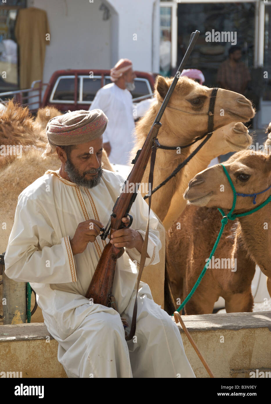 Uomo seduto regolazione vite di fucile mercato di cammelli o souq Sinaw Regione Sharqiya Sultanato di Oman Foto Stock