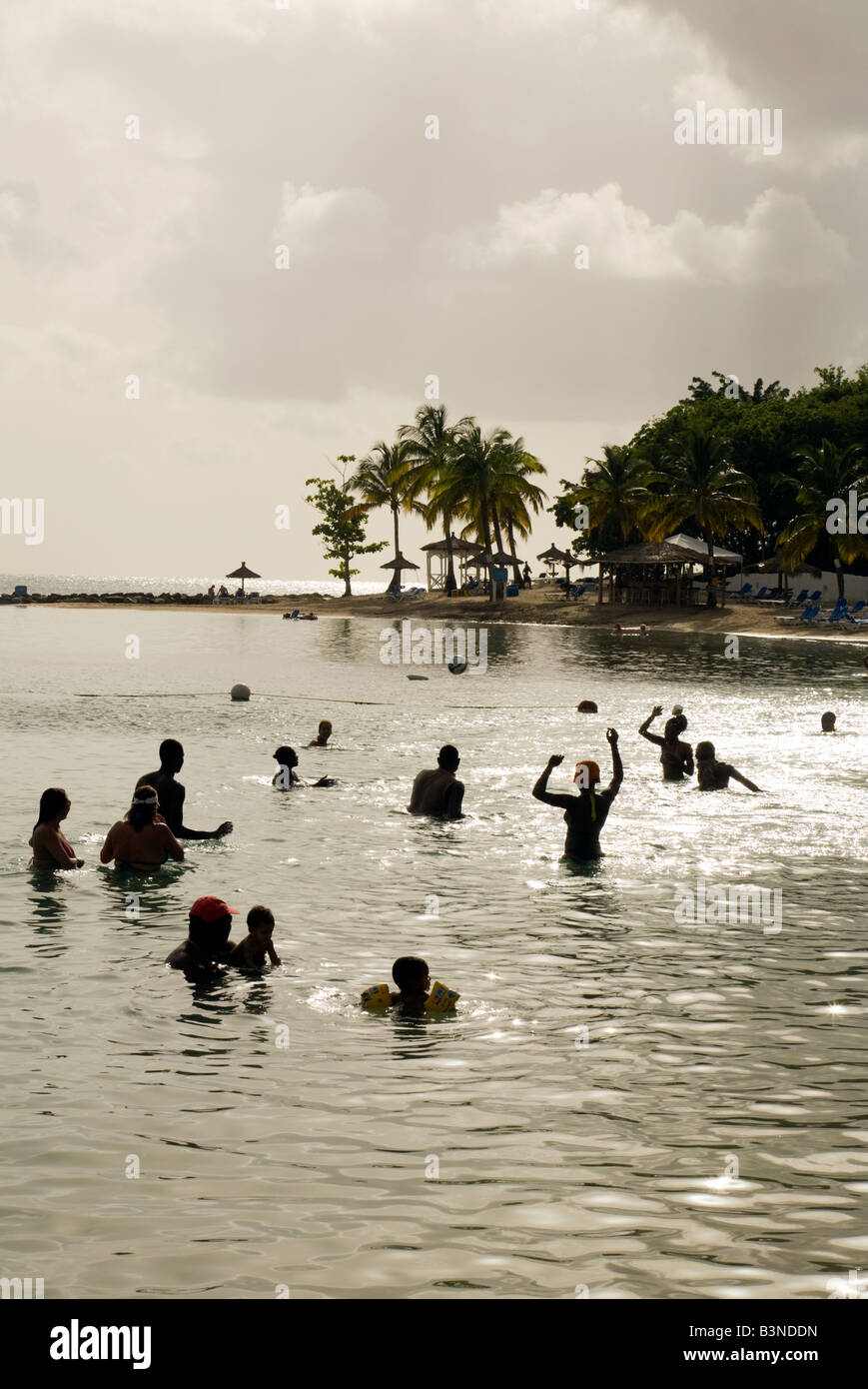 La gente del posto e i turisti giocare a pallanuoto in mare al tramonto, Windjammer Landing, Windjammer Bay, St Lucia, 'West Indies' Foto Stock