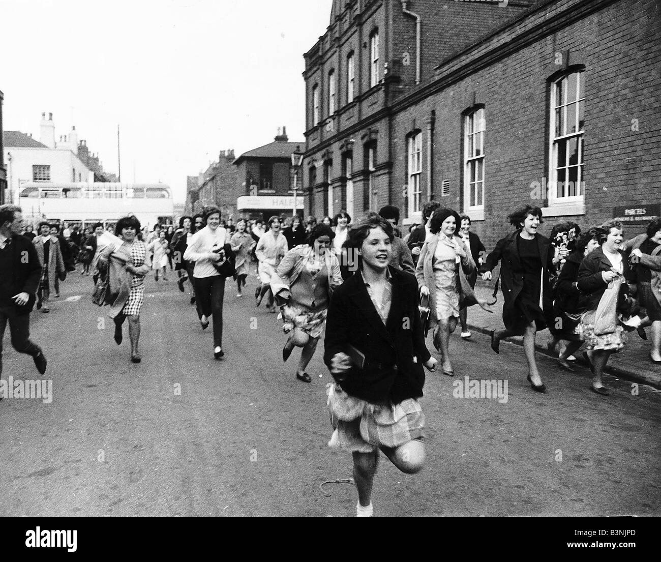 I fan dei Beatles rush in giù lungo la strada verso la macchina portante il gruppo di Birmingham in circa 1964 Foto Stock