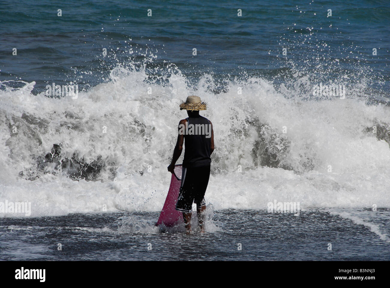 Uomo di ciottoli di raccolta come il surf va in e out,kusamba ,bali , Repubblica di Indonesia Foto Stock