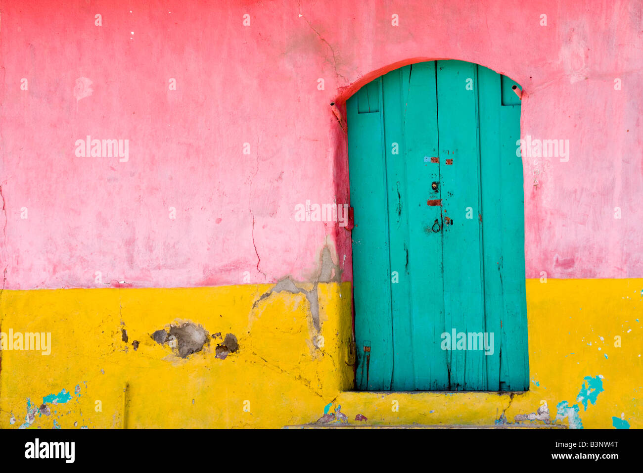 Una parete e porta usurato e scheggiati dal passare del tempo questo è un tipico tipo di vernice utilizzata sull'architettura coloniale di Foto Stock