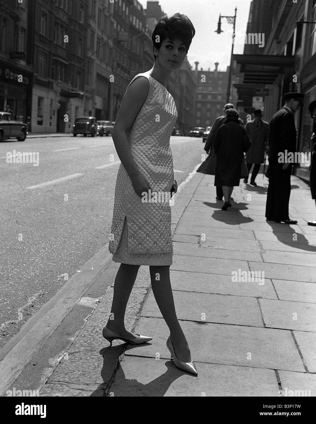 Moda degli anni Sessanta da Kiki Byrne modello indossando abito bianco con feritoie per la coscia e pattened dettaglio sul mantello Foto Stock
