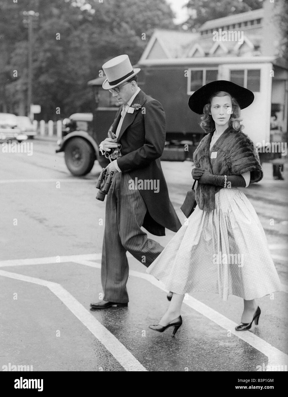 1953 Abbigliamento Moda Ascot onorevole R R Barder con una immagine nera cappello e una stola di minx arriva per le gare di attraversare la strada Foto Stock