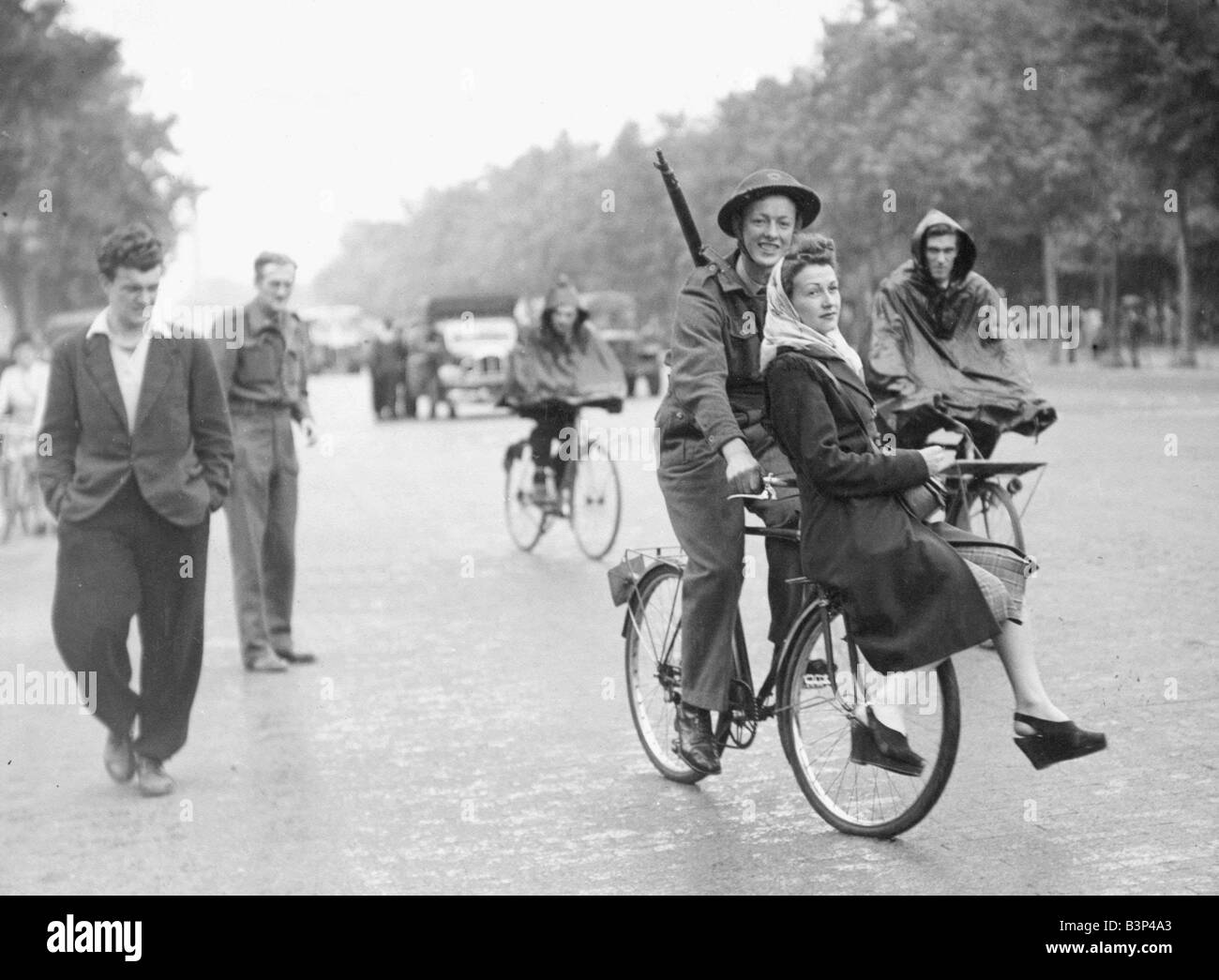 WW2 agosto 1944 LAC Stanley Mallett RAF dando una ragazza francese di un ascensore su una bici in prestito che indossano uniformi e casco di stagno con un fucile espulso sulla spalla Foto Stock