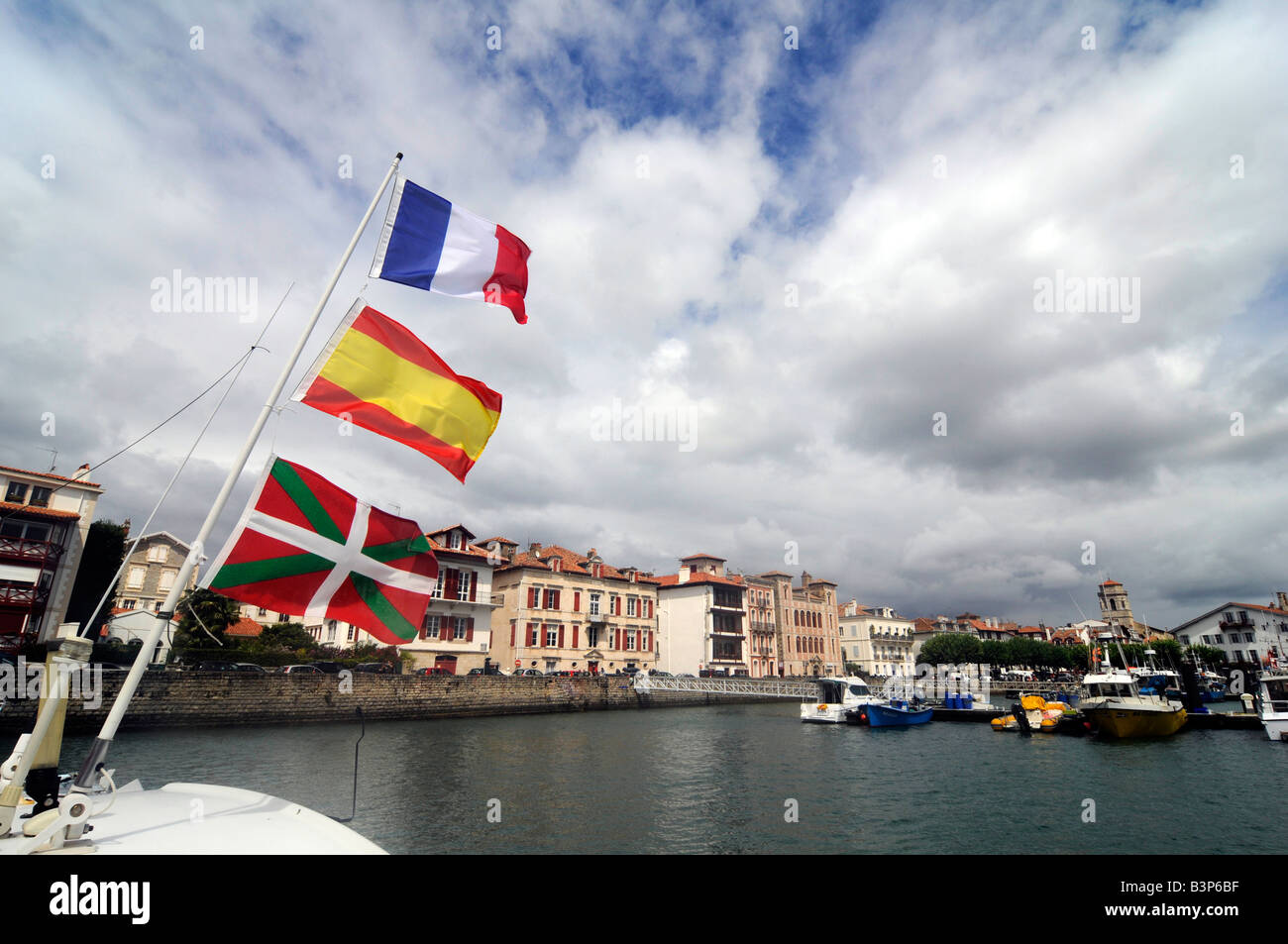 Tre bandiere che sventolano da una barca il montante, dal basso verso l'alto: basco bandiera, la bandiera spagnola, bandiera francese, in St Jean de Luz, Francia Foto Stock