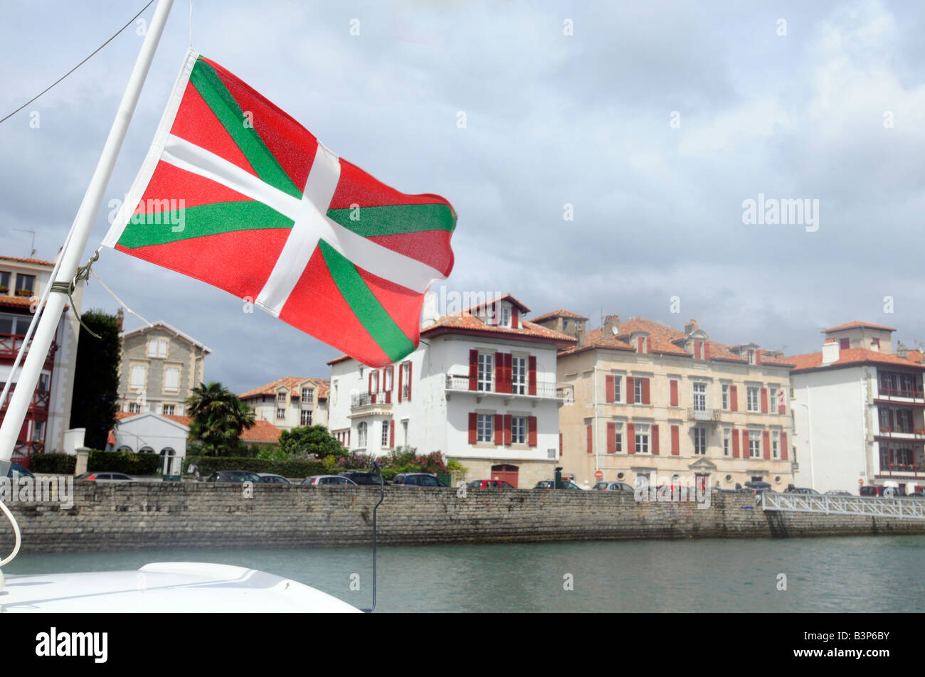 Una bandiera basca vola da una barca è il montante nel porto di St Jean de Luz, una piccola città nel Pays Basque, il sud-ovest della Francia Foto Stock