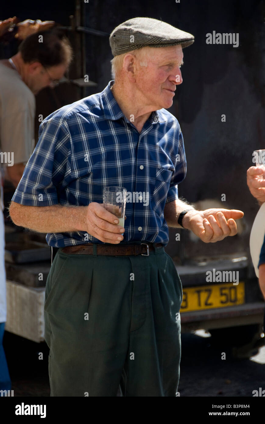 Al mercatino di vendita a Barneville, Normandia, Francia. Un agricoltore anziano con un bicchiere di pastis o ricard Foto Stock