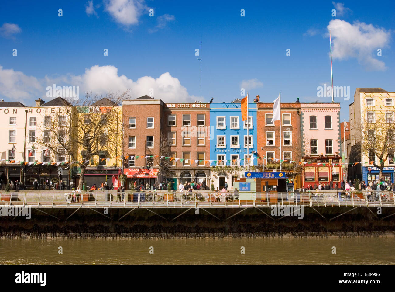 Gli edifici colorati e bandiere irlandesi sui laureati a piedi sulle rive del fiume Liffey, Dublino, Irlanda Foto Stock