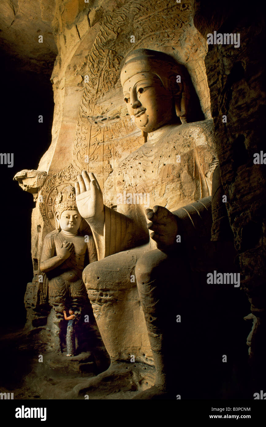 Cina, Datong. Visitatore accanto a una delle statue del Buddha al quinto secolo le grotte di Yungang, una serie di grotte buddista Foto Stock