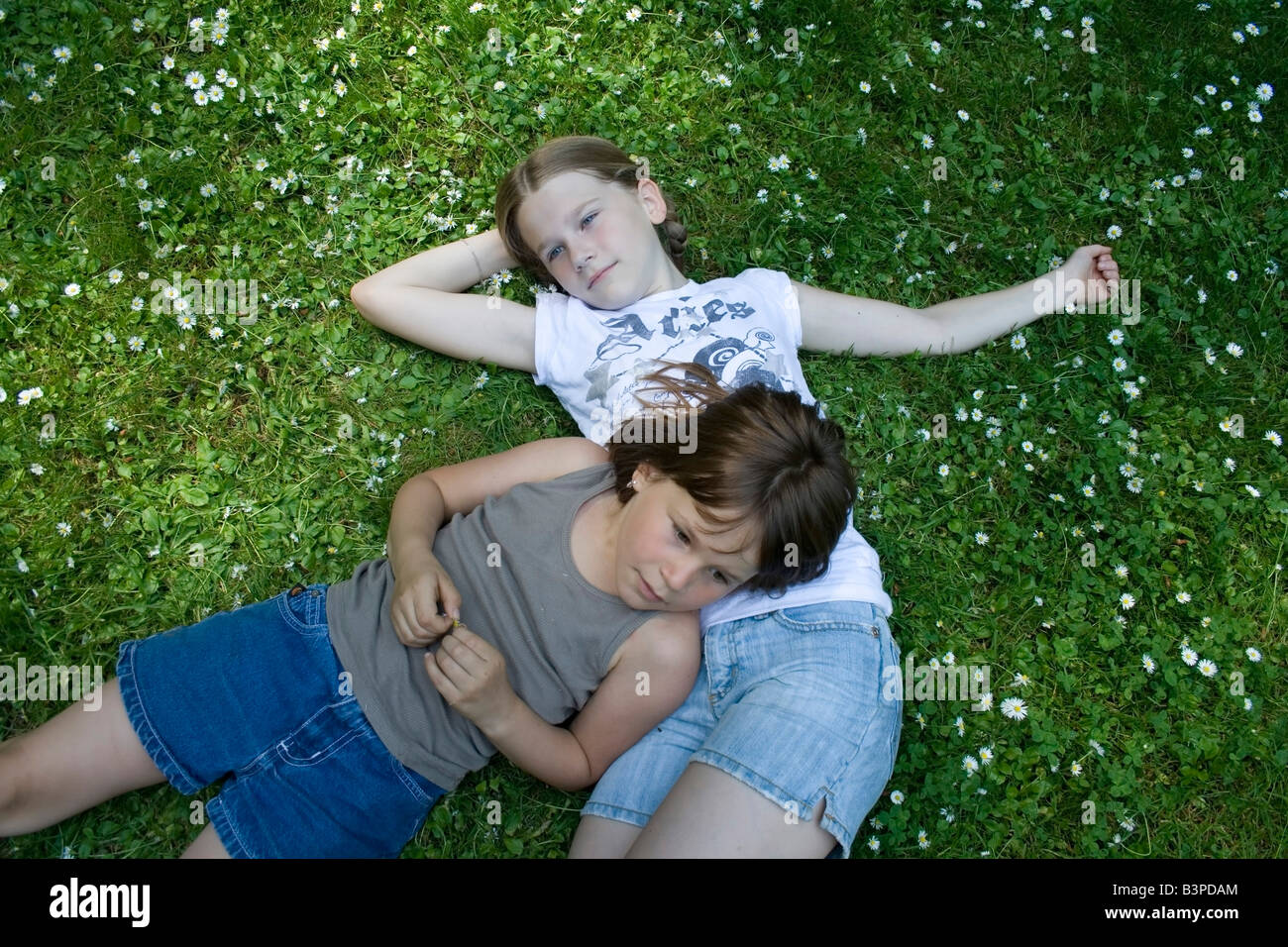 Due giovani ragazze giacente in erba pieno di margherite Foto Stock