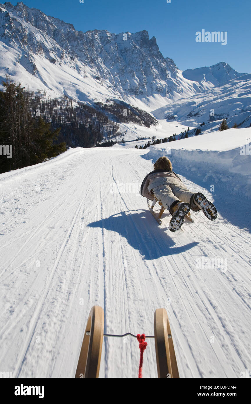 La Svizzera, dei Grigioni, Savognin, ragazzo (8-9) lo slittino, vista posteriore Foto Stock