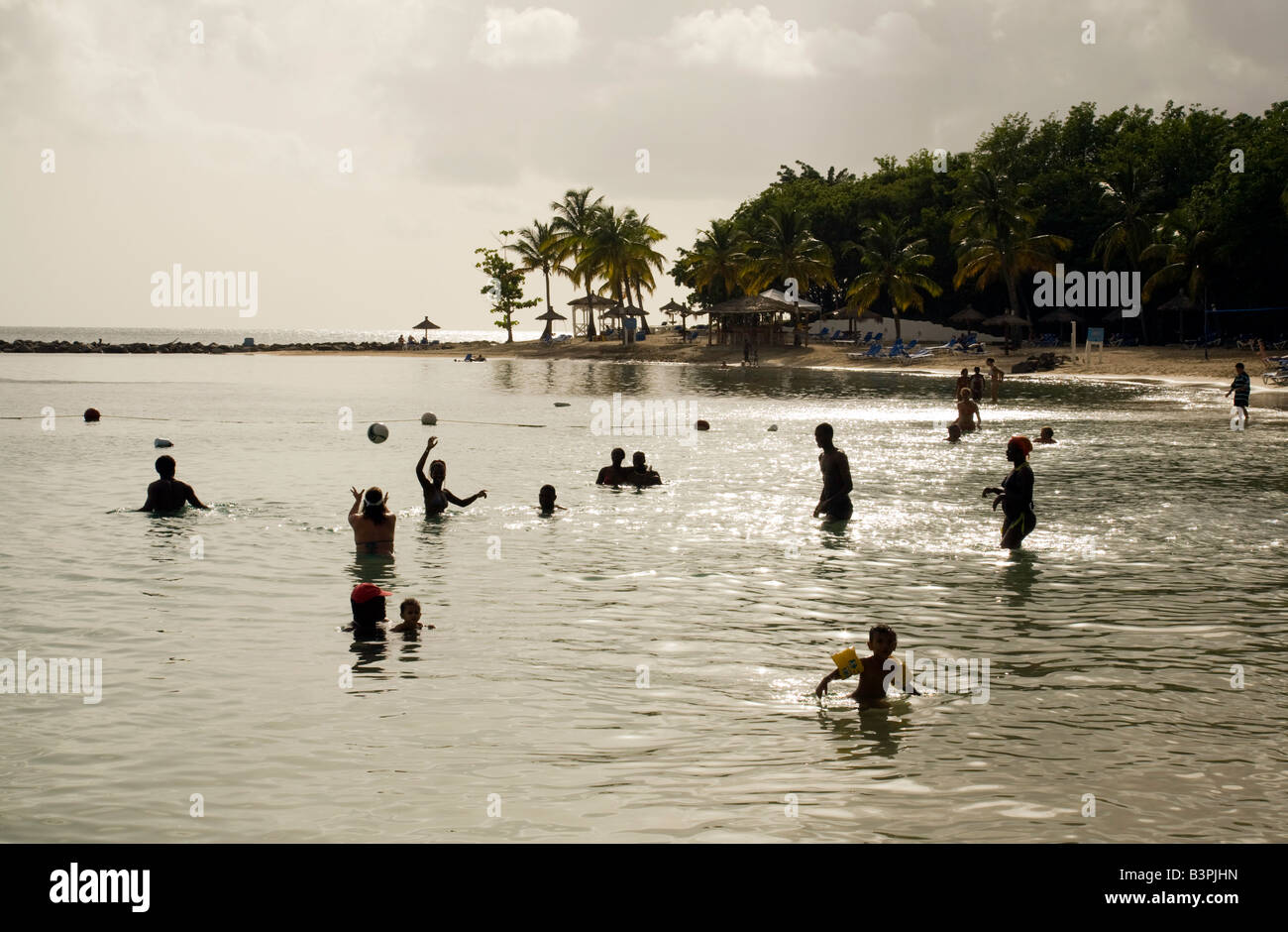 La gente del posto e i turisti giocare a pallanuoto in mare al tramonto, Windjammer Bay, St Lucia, 'West Indies' Foto Stock