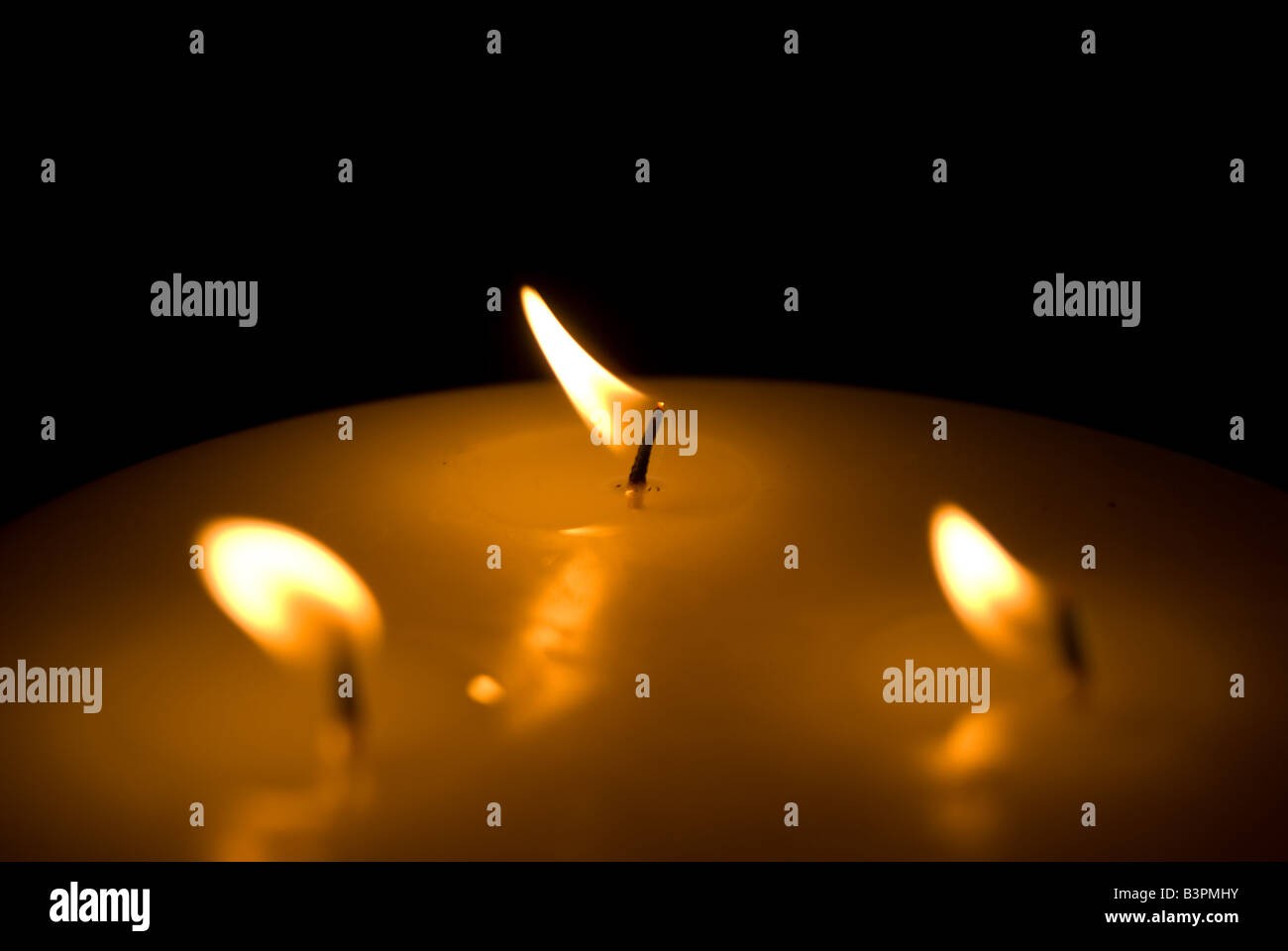 Tre fiamme bruciare vivacemente su una candela di grandi dimensioni Foto Stock